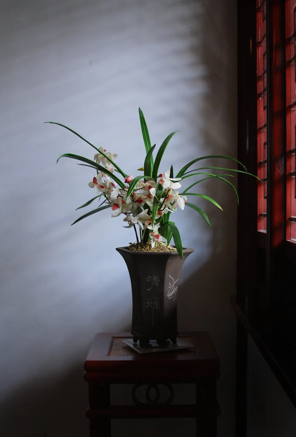 Blumenarrangement vor einem lichtschwachen Fenster